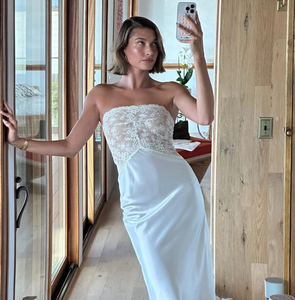 Hailey Bieber showcases a bridal slip dress in a mirror selfie